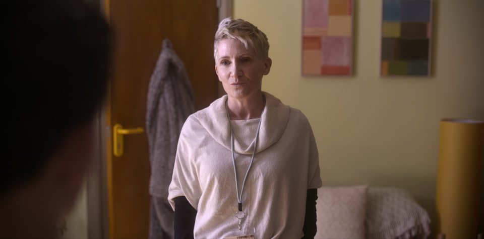 a woman in a white sweater has a name tag around her neck