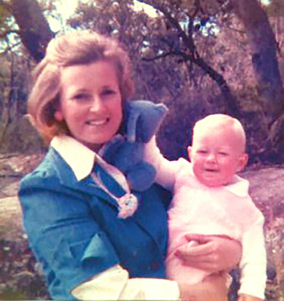 a woman in a blue jacket is holding a baby in her arms