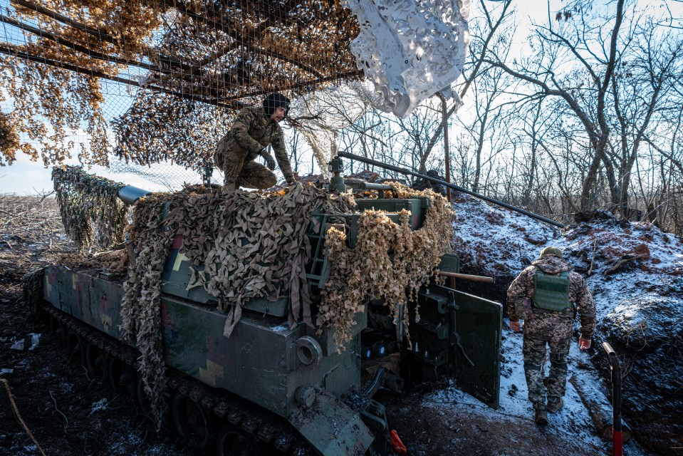 Ukrainian soldiers stand by a M109 artillery self-propelled vehicle on the front line, in the direction of Bakhmut