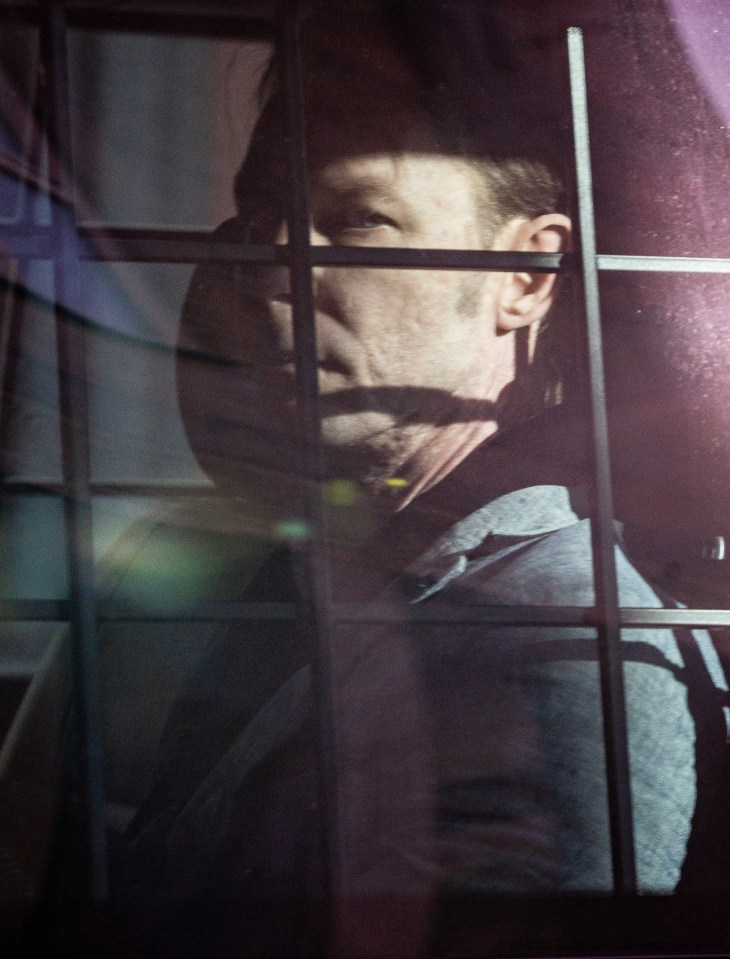 a man behind bars with a reflection of him in the glass