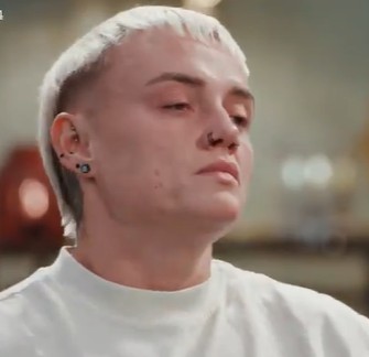 a close up of a man 's face with a nose ring and earrings .