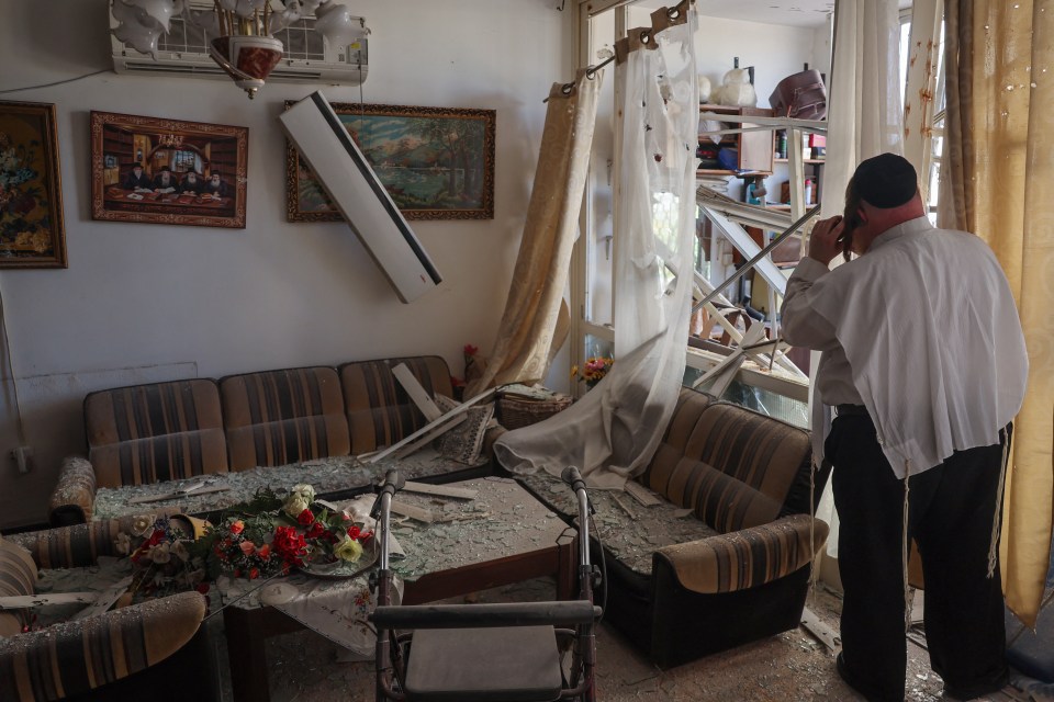 An Israeli man inspects the damage in his apartment after a Hezbollah rocket blitz today