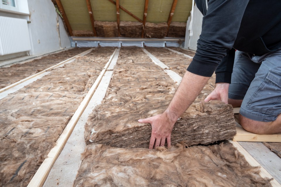 a man is kneeling down holding a roll of insulation