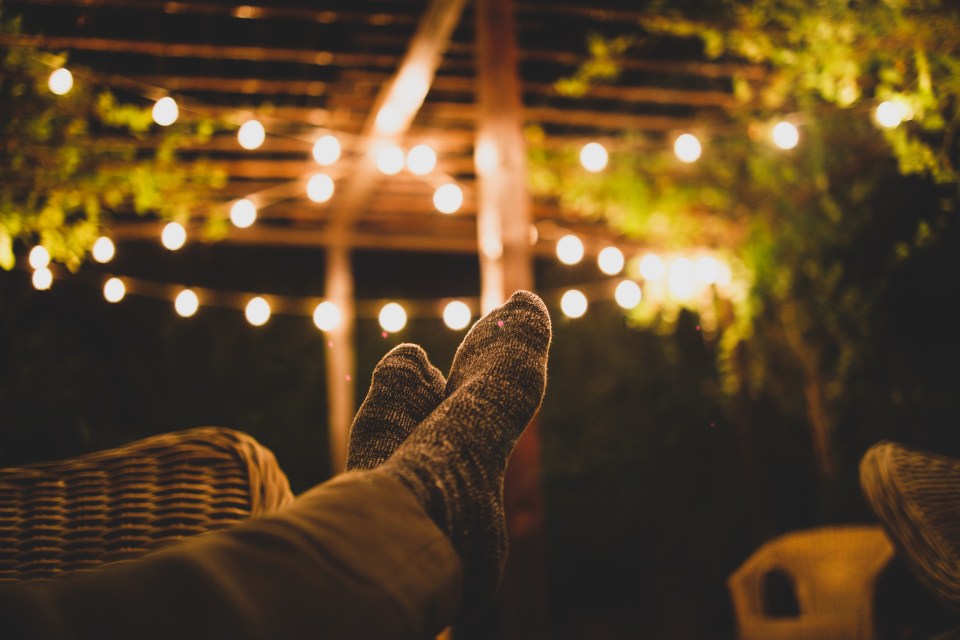 a person laying on a chair with their feet up and a string of lights in the background