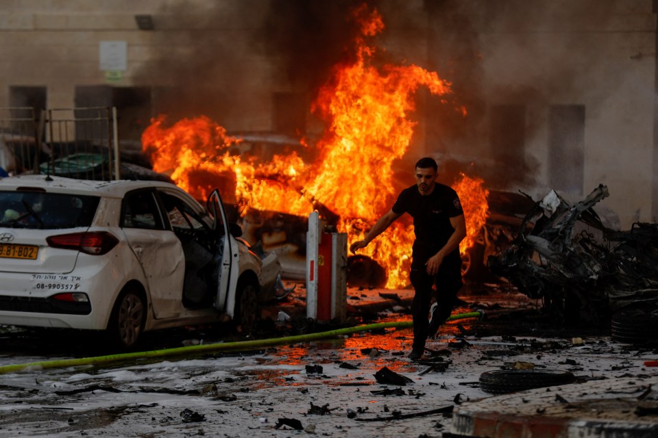 A man runs on a road as fire burns after rockets were launched from the Gaza