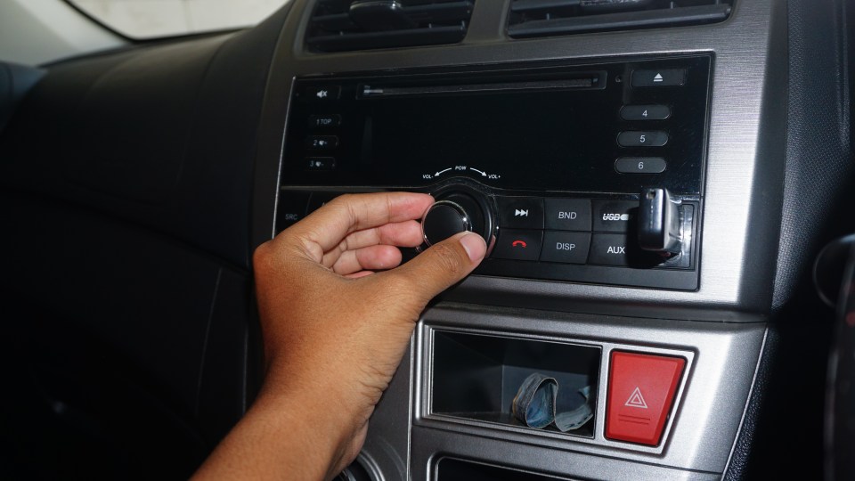 a person is adjusting the volume on a car radio