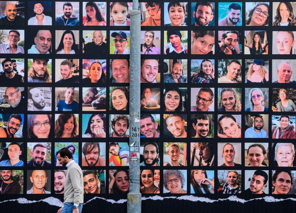 A man walks past a giant billboard featuring portraits of Israeli hostages held in Gaza since the October 7 attack by Hamas