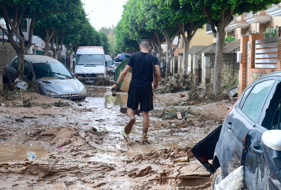 A man walks in a street covered in mud in a flooded area in Picanya, near Valencia