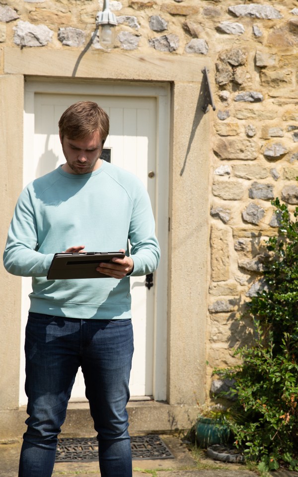 a man standing in front of a stone building looking at a tablet