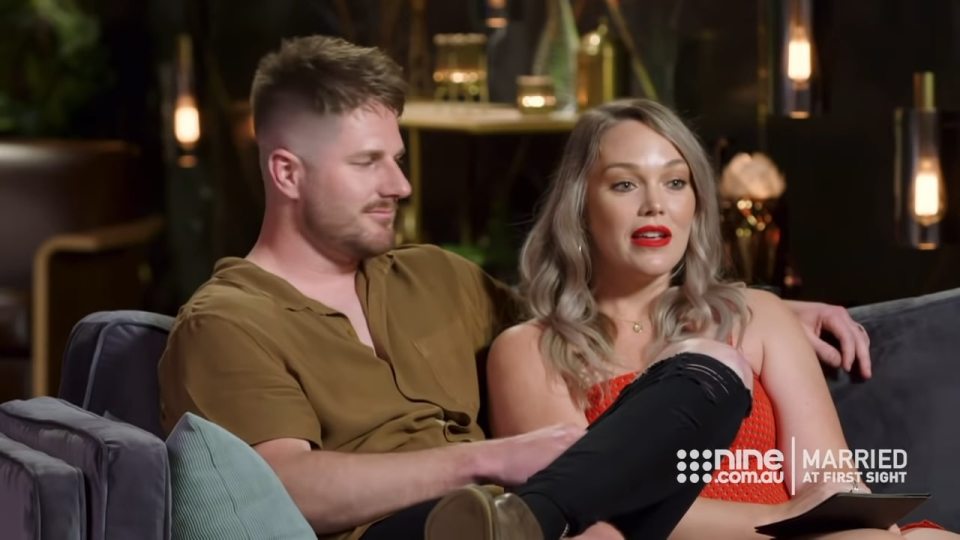 a man and a woman sit on a couch with the words married at first sight on the bottom