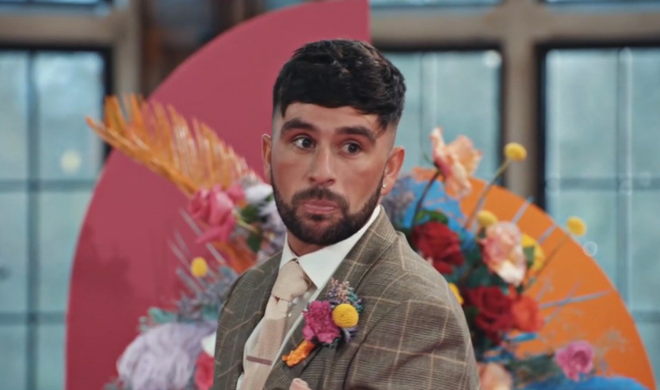 a man in a suit and tie is standing in front of flowers