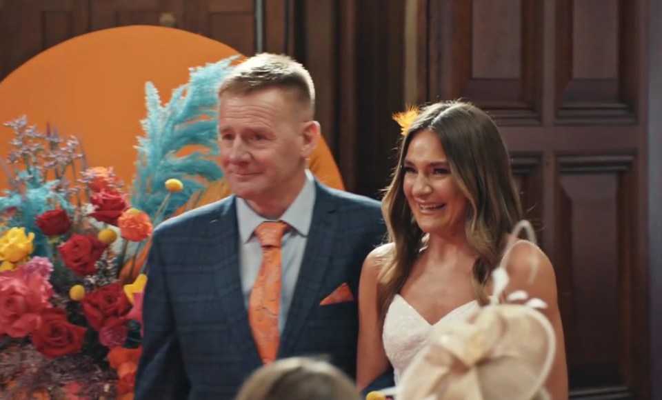 a man in a suit and tie stands next to a woman in a white dress