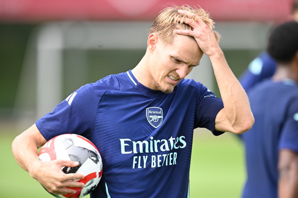 a man wearing an emirates fly better jersey holds a soccer ball