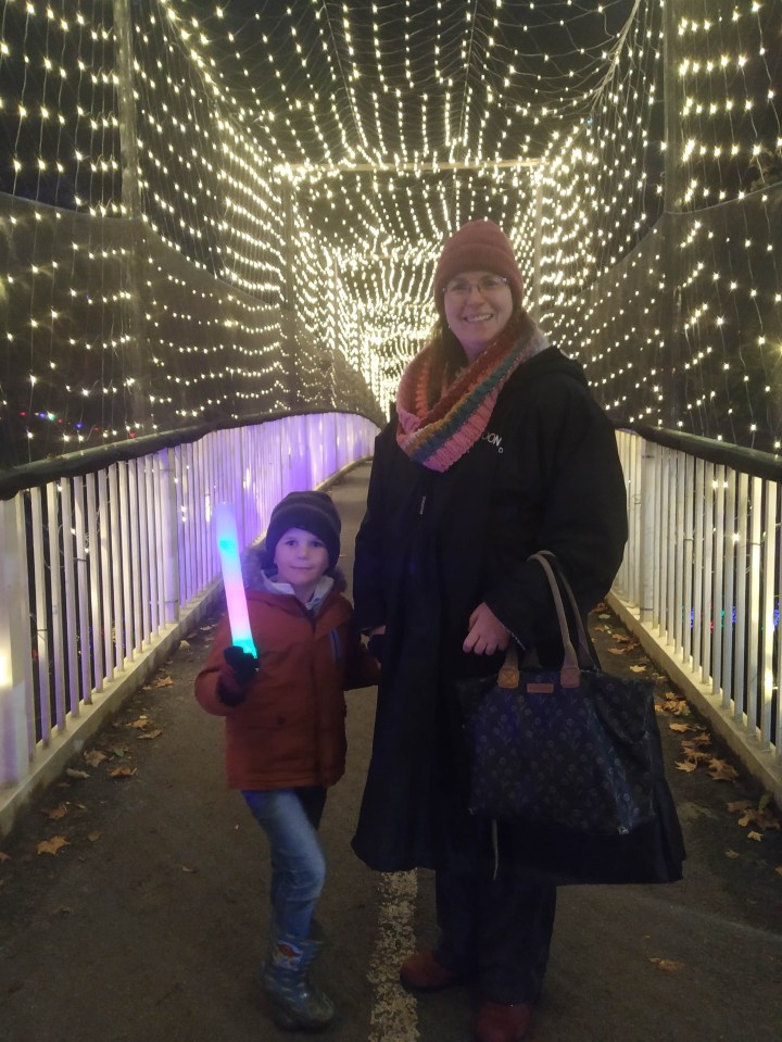 a woman holding a louis vuitton purse stands next to a boy holding a light stick