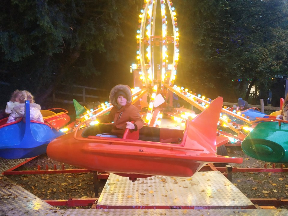 a boy in a furry hat is riding a carnival ride