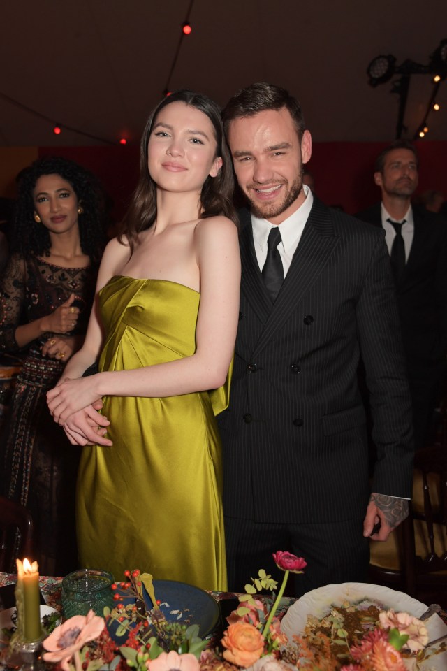 a man in a suit and tie stands next to a woman in a green dress