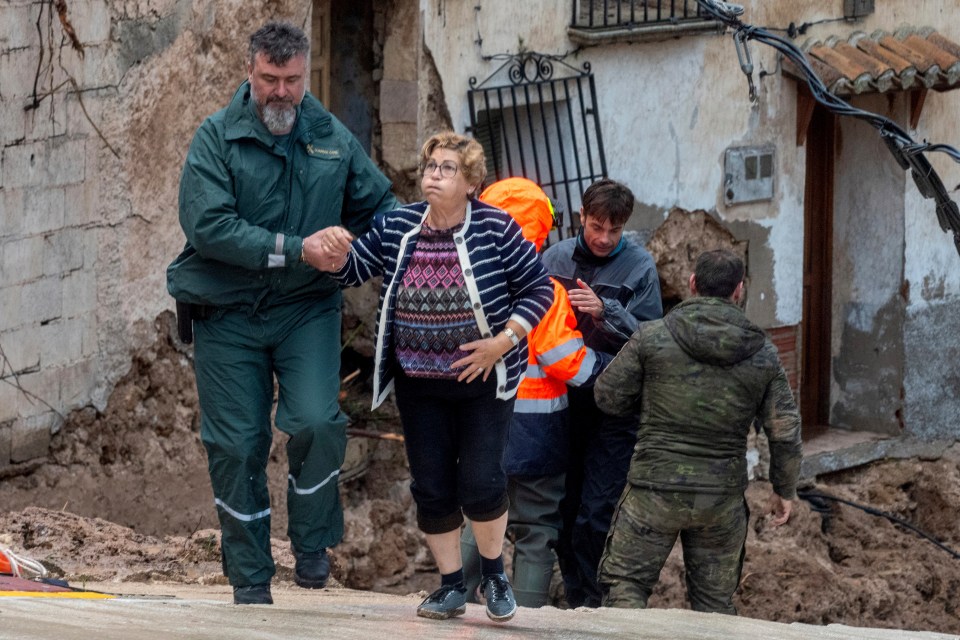 A Spanish soldier and emergency worker evacuate trapped locals after the floods