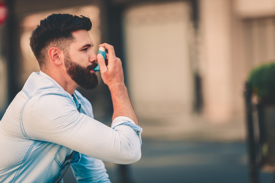 a man in a blue shirt is using an inhaler