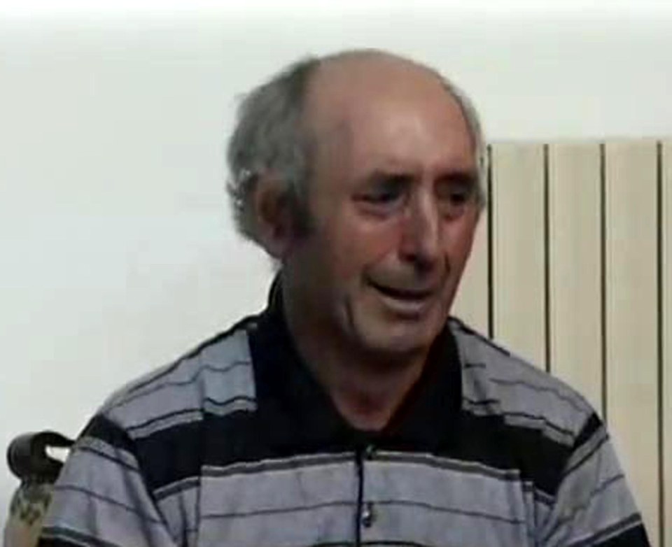 a bald man is sitting in front of a radiator wearing a striped shirt .