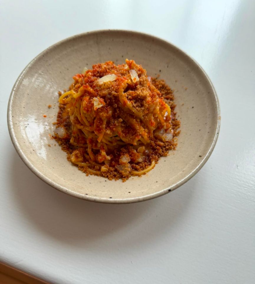 a bowl of spaghetti with sauce and crumbs on top