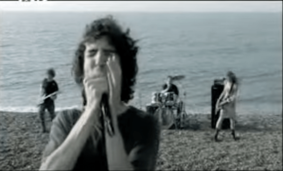 a man is singing into a microphone on the beach