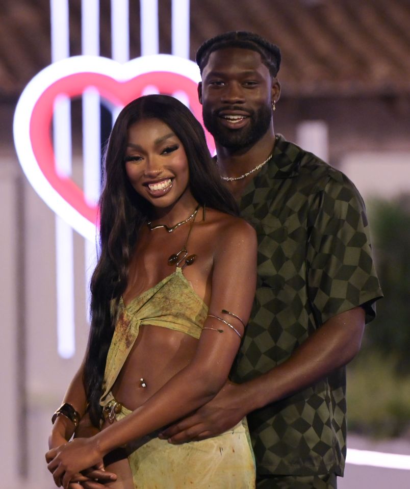 a man and a woman are posing for a picture in front of a heart sign