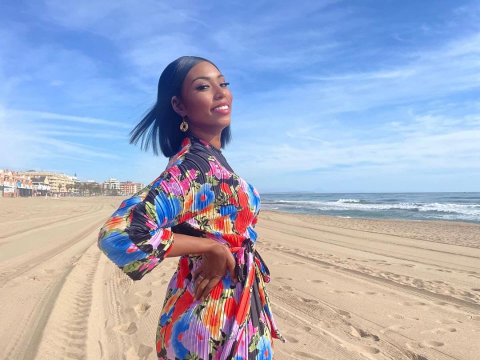 a woman in a colorful dress is standing on a beach