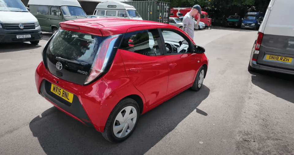 a red toyota aygo is parked in a parking lot