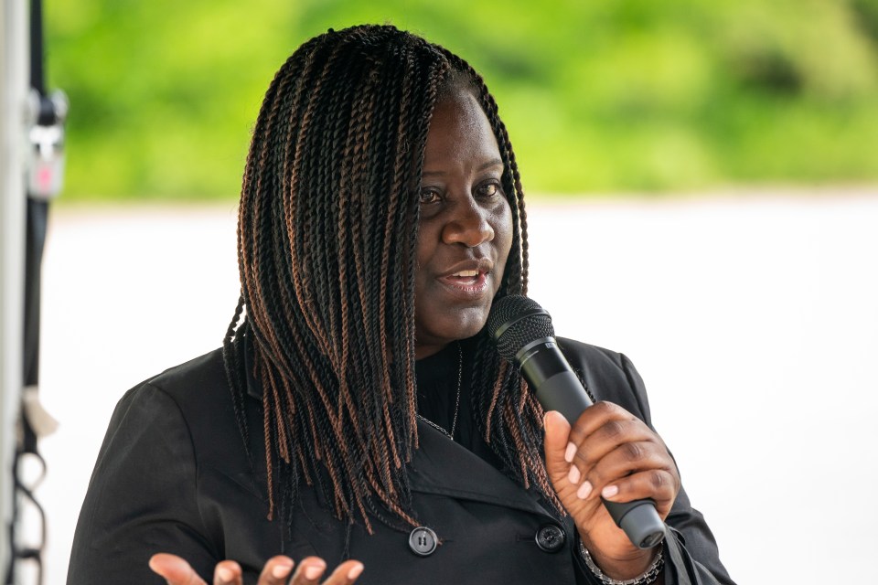 a woman speaking into a microphone with the name marsha de cordov behind her