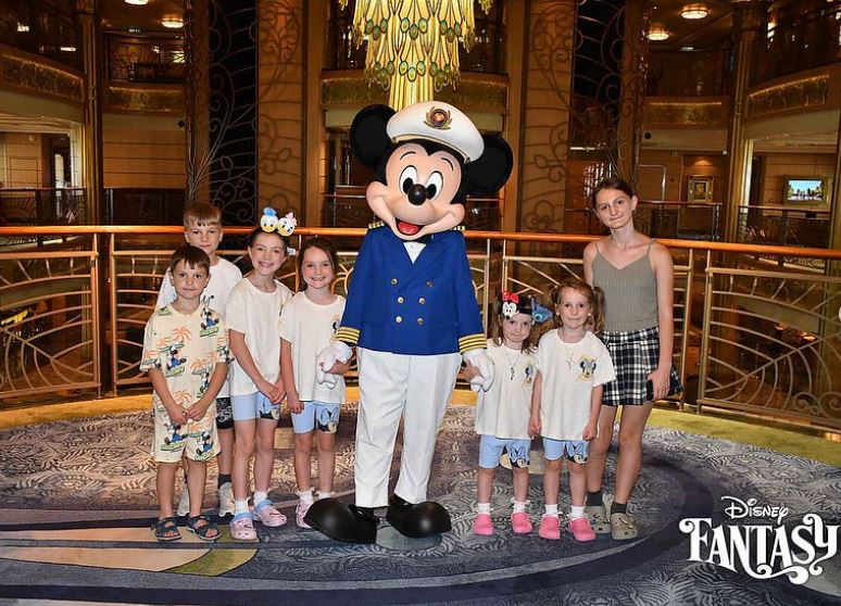 a group of children pose with mickey mouse in a disney fantasy photo