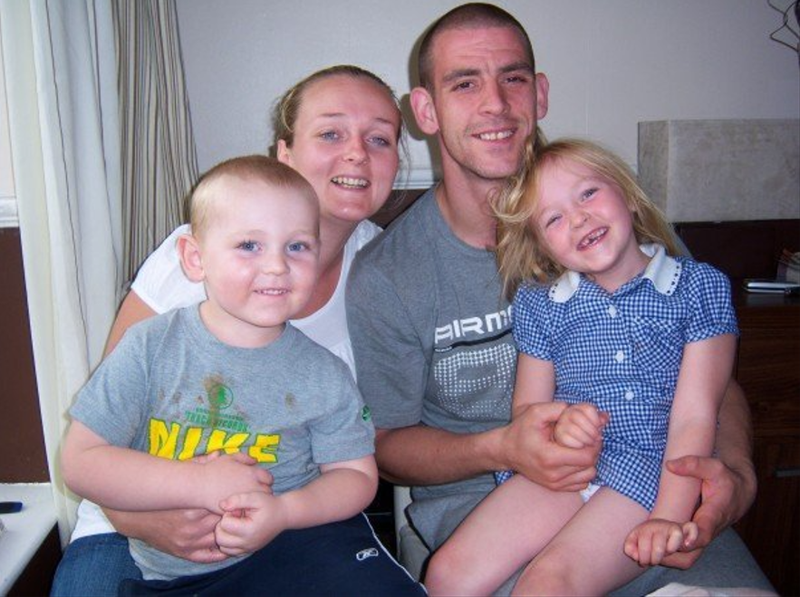 a family posing for a picture with a man wearing a nike shirt