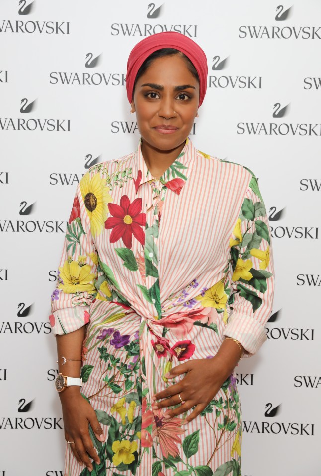 a woman stands in front of a wall that says swarovski