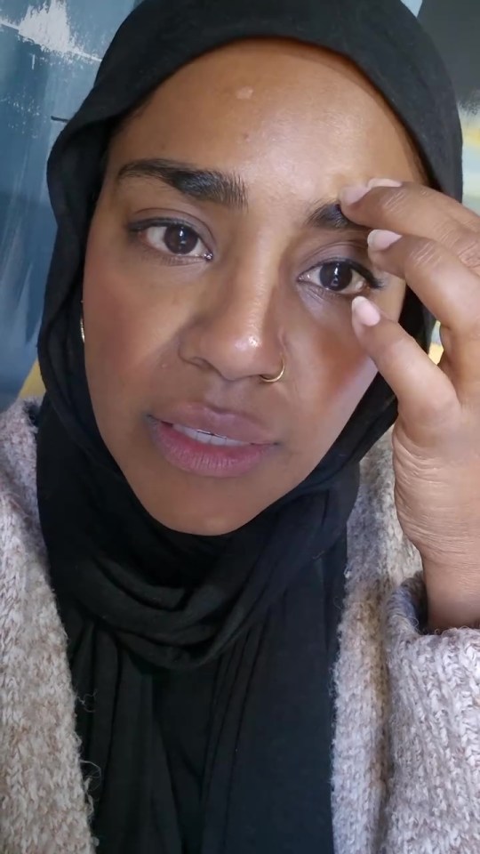 a woman wearing a black hijab and a gold nose ring