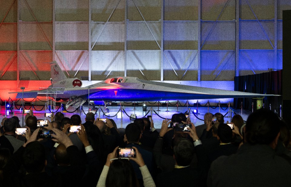 a group of people are taking pictures of a fighter jet in a hangar