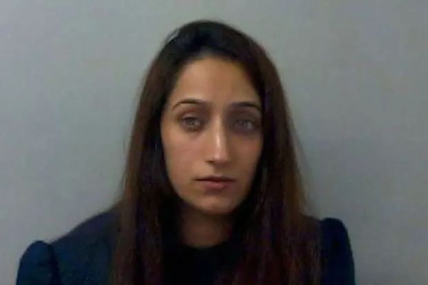 a woman with long hair is sitting in front of a white wall and looking at the camera .