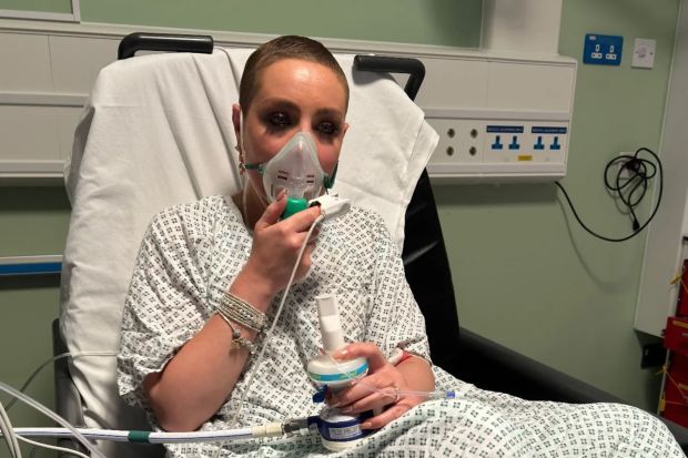 a woman wearing an oxygen mask sits in a hospital bed