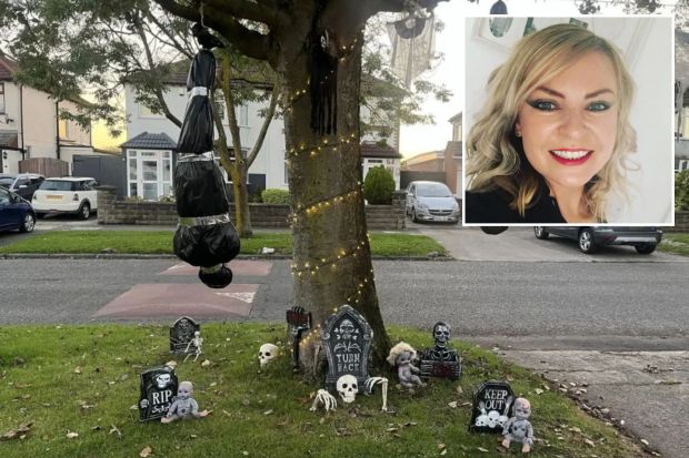 a woman is smiling next to a tree decorated for halloween