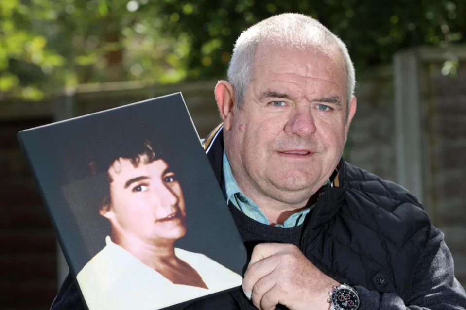 a man in a black jacket holds a picture of a woman