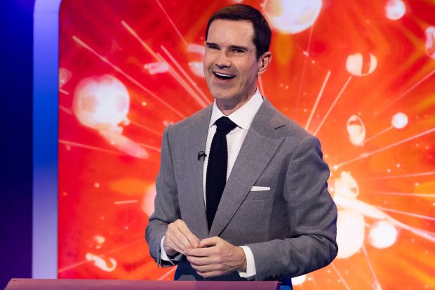 a man in a suit and tie stands in front of a red background