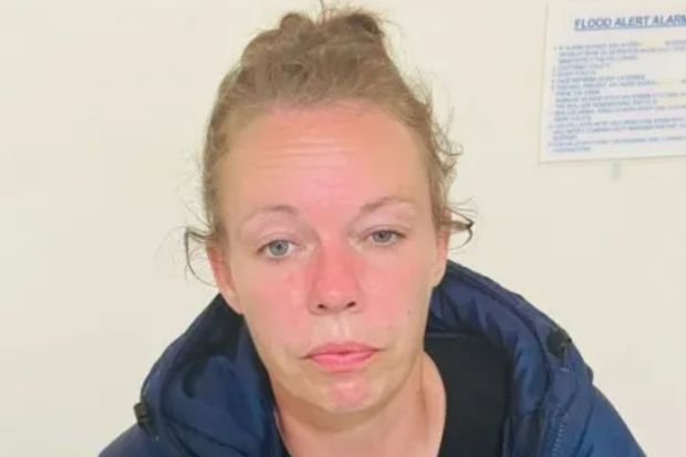 a woman with a red face is sitting in front of a flood alert sign .