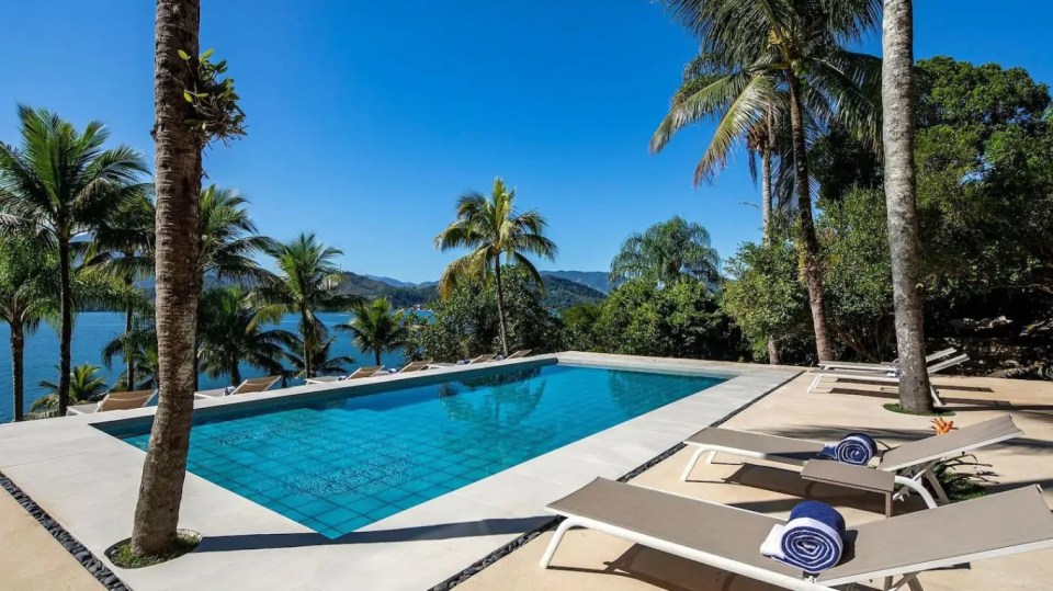 a large swimming pool surrounded by chairs and palm trees