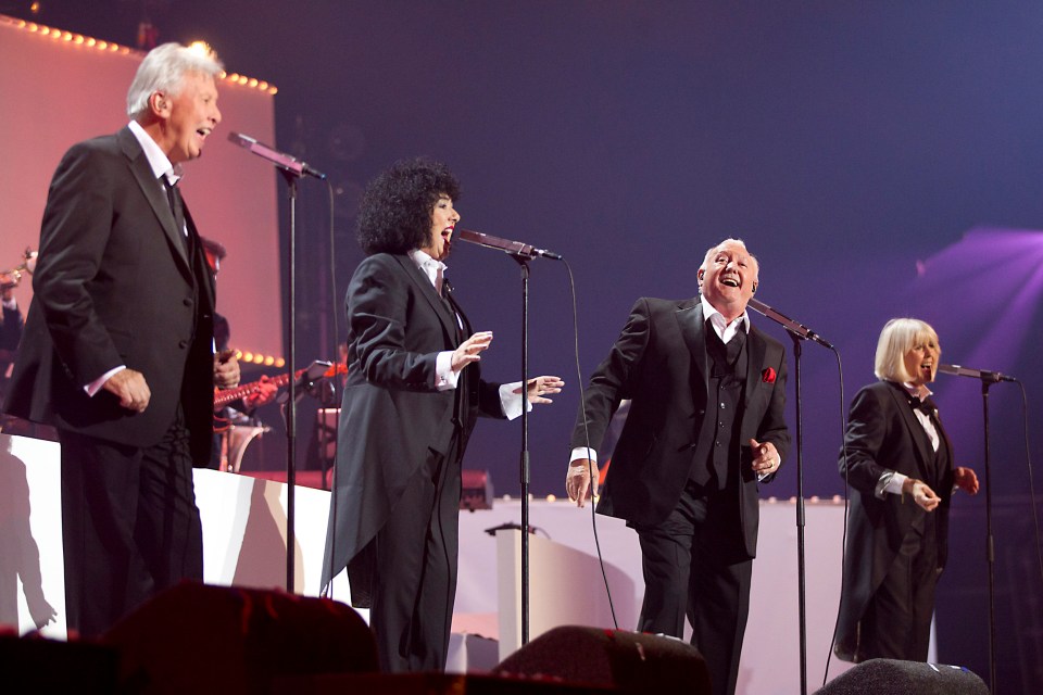 a group of people singing into microphones on a stage