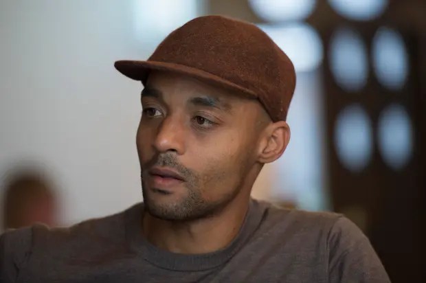 a man wearing a brown hat and a gray shirt is looking at the camera .