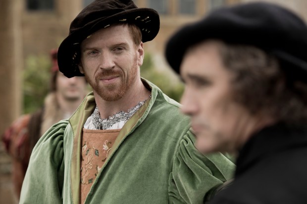 a man with a beard wears a green coat and a black hat