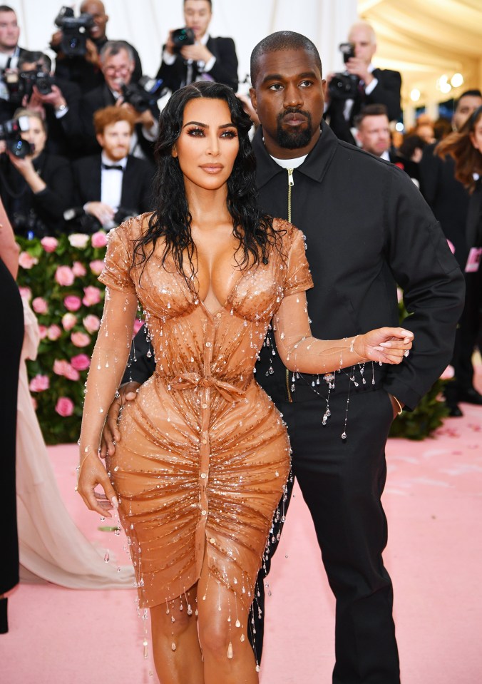 kanye west and kim kardashian pose for a picture on a pink carpet