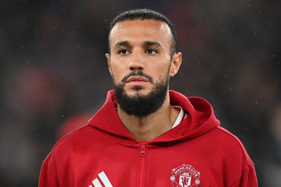 a man with a beard wears a red manchester united jacket