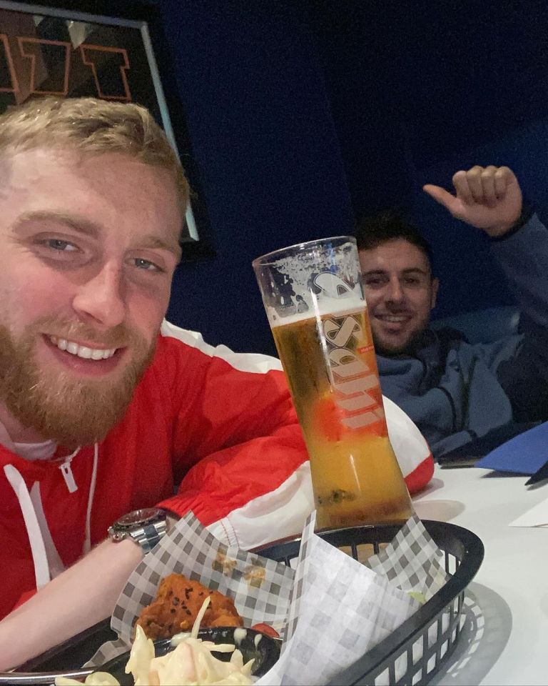 two men sitting at a table with a glass of smirnoff beer