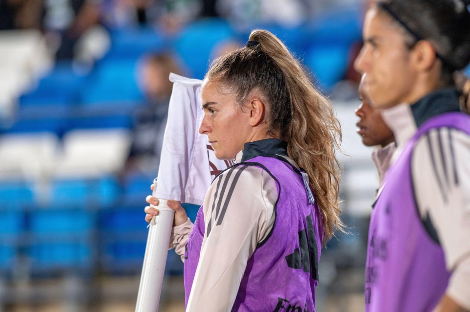 a woman in a purple adidas vest holds a white flag