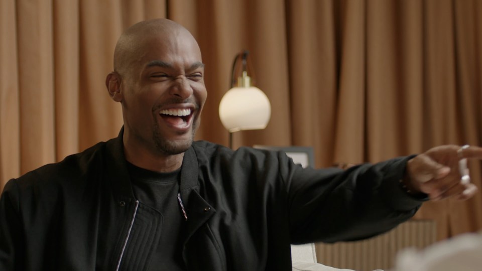 a man in a black jacket is laughing with his mouth open