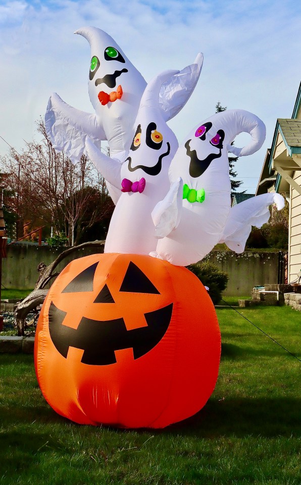 three inflatable ghosts are standing on top of an orange pumpkin